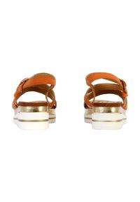 Orangefarbene Sandalen verfügen über zwei Riemen, eine Schnallendetail und eine weiß-gold akzentuierte Sohle. Das Design beinhaltet einen leichten Absatz für zusätzliche Höhe.