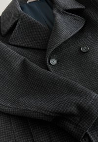 Dark gray wool coat with houndstooth texture, wide lapels, double-breasted button closure, and smooth inner lining.