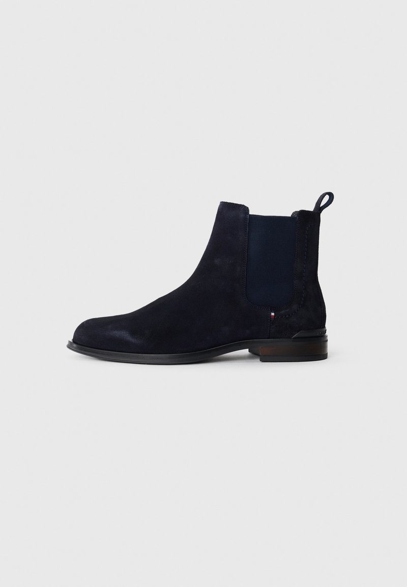 Dunkelblaue Wildleder Chelsea-Boots mit elastischen Seiteneinsätzen, Ziehlasche hinten und niedrigem Blockabsatz vor einem schlichten hellen Hintergrund.