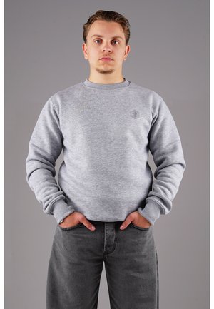 Grauer Sweatshirt mit geripptem Rundhalsausschnitt und Bündchen. Verfügt über ein kleines Logo auf der Brust. Eine dunkelgraue Jeans rundet den Look ab.