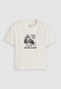 Vit bomulls-t-shirt med en svart grafik av en bassetthund och texten "HAD A RUFF DAY? I’M ALL EARS!" i fet stil. Korta ärmar.
