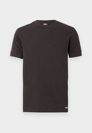 Sort kortærmet t-shirt med rund hals og ribbet krave og ærmer, lille hvidt logo tæt på den nedre kant på en ensfarvet baggrund.