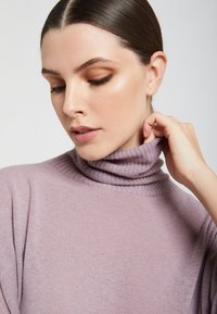 Jasnofioletowy sweter z golfem o ribbowanym kołnierzu i miękkiej fakturze, charakteryzujący się luźnym krojem i minimalistycznym stylem.