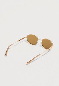 Kerek napszemüveg barna lencsékkel, arany színű fém kerettel és vékony szárakkal, amelyek texturált mintázattal rendelkeznek.