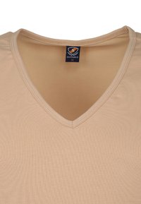 Beige v-hals t-shirt van zacht, rekbaar materiaal met ribbeltextuur en nette stiksels. Het label bij de hals geeft maat medium aan.