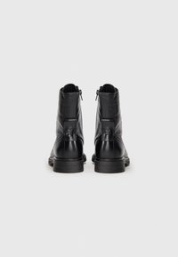 Black leather ankle boots with a smooth finish, featuring a zip closure and decorative stitching. Sturdy rubber sole with slight heel.