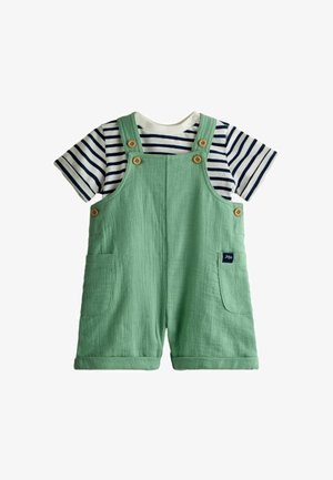 Žalios spalvos medvilniniai trumpi kombinezonai su kišenėmis ir mediniais mygtukais, dėvimi ant baltos ir tamsiai mėlynos dryžuotos trumpomis rankovėmis marškinėlių, skirti mažyliams.