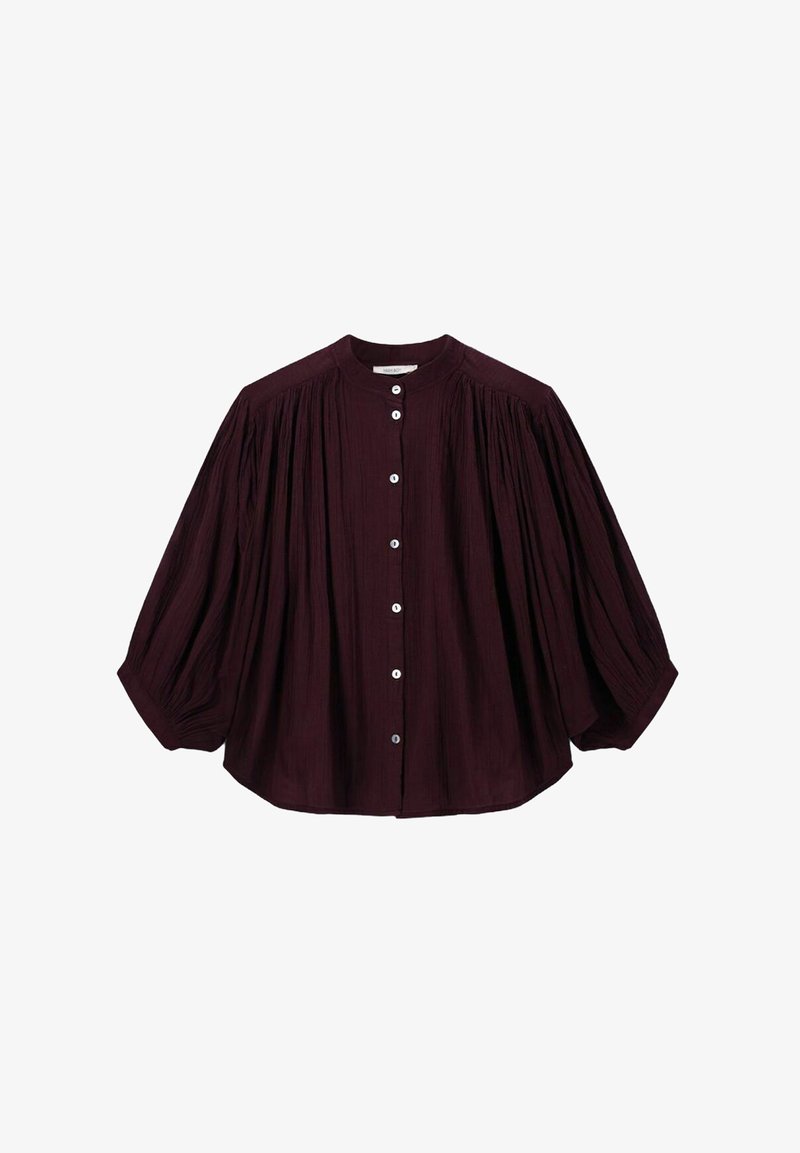 Dark purple long-sleeve blouse with gathered fabric details, round neckline, and white front buttons, creating a loose, flowy silhouette.