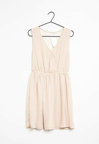 Světle růžové bezramínkové šaty s v-dekoltem, elastickým pasem a splývavou sukní; mají krajkový detail u zadního výstřihu.