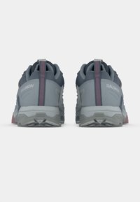 Ανδρικά παπούτσια Salomon για trail με γκρι επάνω μέρος από πλέγμα, επενδεδυμένο γιακά, αντίθετες ροζ λεπτομέρειες και ανθεκτική γκρι σόλα. Παρουσιάζουν αντανακλαστικές λεπτομέρειες.