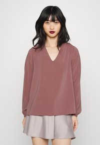 Top de manga longa, cor malva, com decote em V, feito de um tecido suave, combinado com uma mini saia satin cinza claro. Design simples e de corte descontraído.