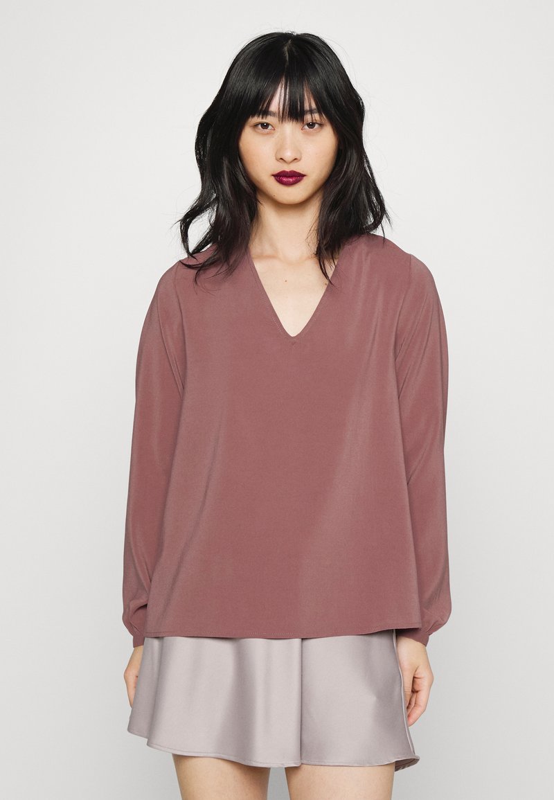 Top de manga longa, cor malva, com decote em V, feito de um tecido suave, combinado com uma mini saia satin cinza claro. Design simples e de corte descontraído.