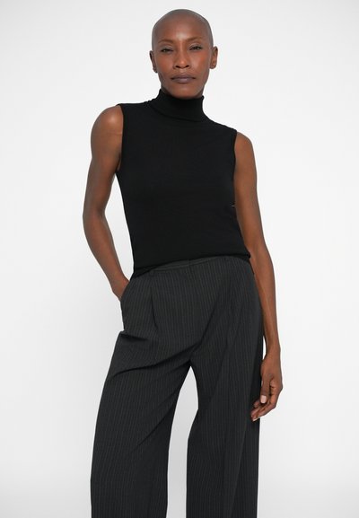 Musta ilmanhiha turtleneck-toppi yhdistetty tummanharmaisiin raidallisiin leveälahkeisiin housuihin, joissa on ribbetty rakenne ja vartalonmyötäinen muotoilu.