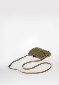 Borsa a tracolla in pelle verde oliva con una trama liscia, pattina ribaltabile, tracolla regolabile e dettagli in metallo nero. Design compatto.
