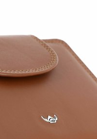 Gros plan d'un portefeuille en cuir marron avec des bords cousus et un petit logo argenté sur une surface lisse.