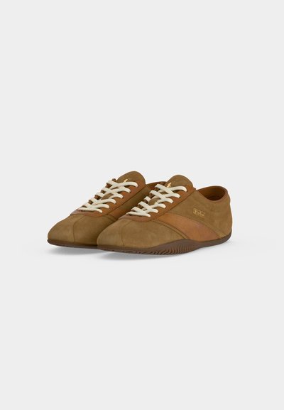 Ζευγάρι καφέ καστόρινων casual sneakers με λευκά κορδόνια και σκουρότερη καφέ ρίγα στις πλευρές πάνω σε απλό ανοιχτόχρωμο φόντο.