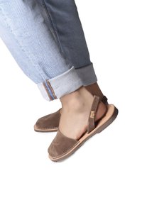 Brune ruskinds slingback sandaler med rund tå og stikninger, parret med lyseblå opstillede jeans.
