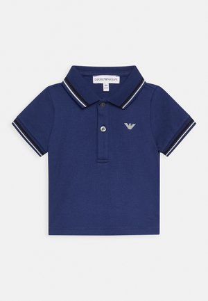 Polo azul-marinho feito de algodão, com colarinho e tapeta de três botões. Apresenta riscas brancas em contraste no colarinho e um logótipo no peito.