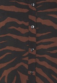 Brown and black striped shirt featuring a button-up front with black buttons, made of a lightweight fabric with a smooth texture.