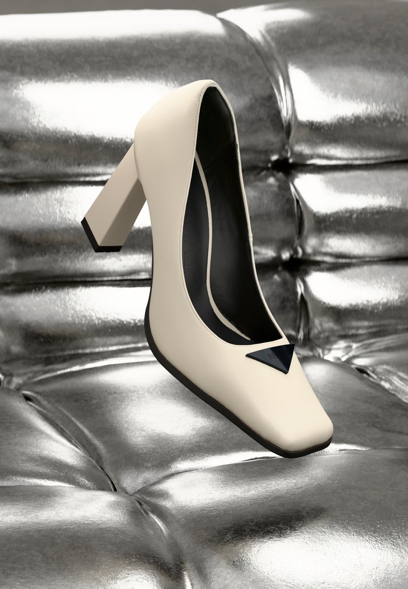 Kreemvärvi nahast kõrged kontsad ruuduotsaga, millel on must kolmnurkne aksent ja paks konts metallik hõbedasel pinnal.