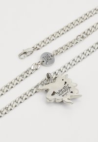 Colar de corrente prateada com um charme texturizado em forma de folha de bordo, gravado com "Don't Hard Designs", com um fecho e etiqueta de logótipo.