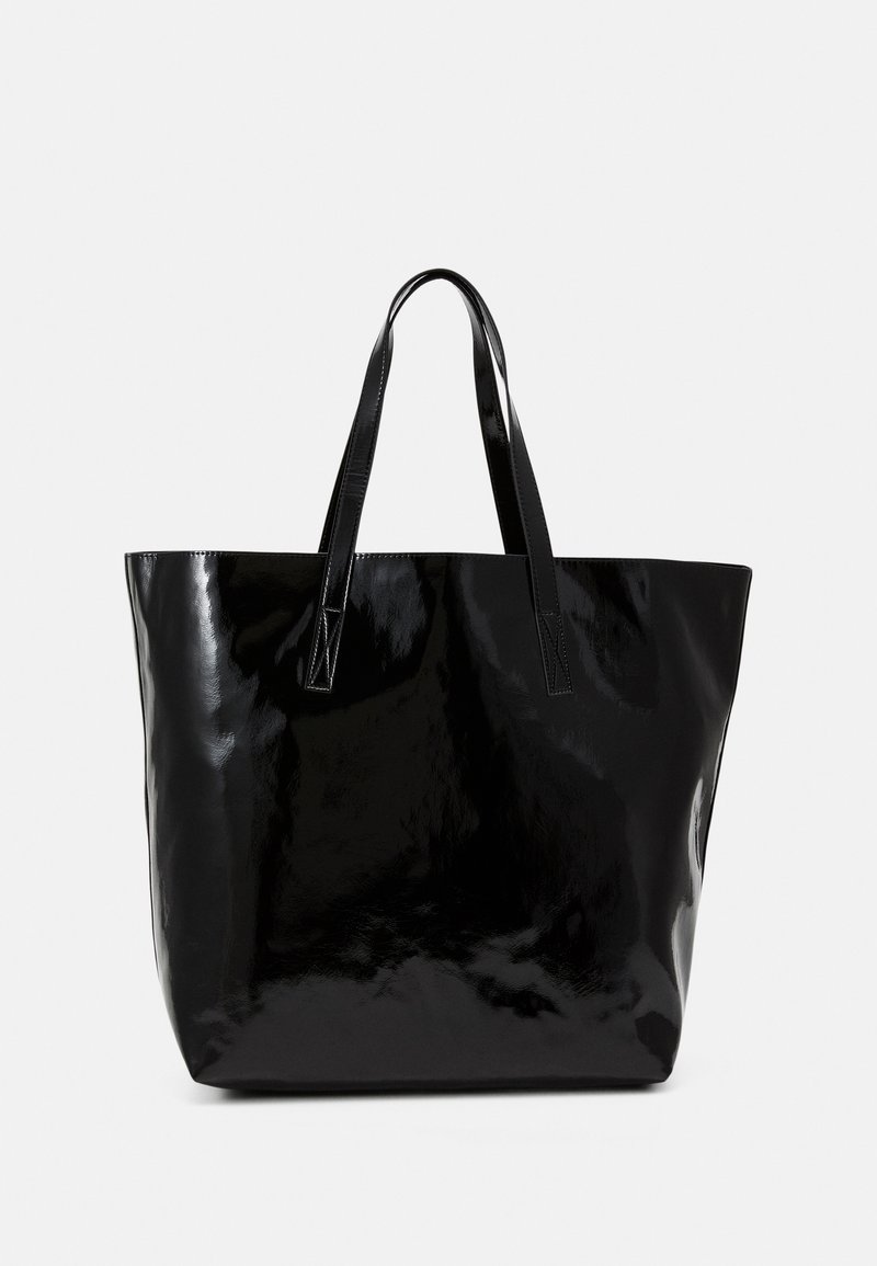 Grand sac fourre-tout noir brillant avec deux longues anses, présenté sur un fond clair uni.