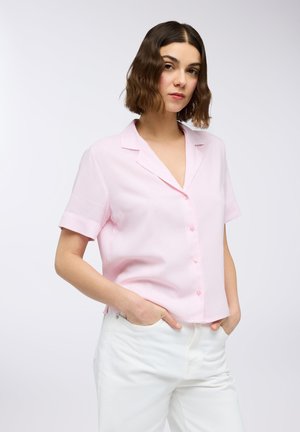 Blusa a maniche corte rosa a righe con scollatura a V e chiusura con bottoni. Il tessuto appare leggero; presenta una vestibilità rilassata e maniche arrotolate.