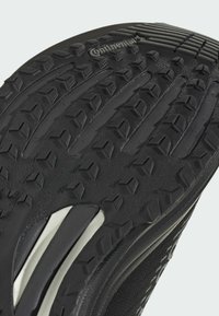 Sort gummisål til sko med dybe, teksturerede slidbaner i et geometrisk mønster; inkluderer en hvid accent og "Continental"-branding.