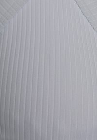 Tecido branco com nervuras e um padrão texturizado. O material parece leve e elástico, apresentando um brilho sutil e um design estruturado.
