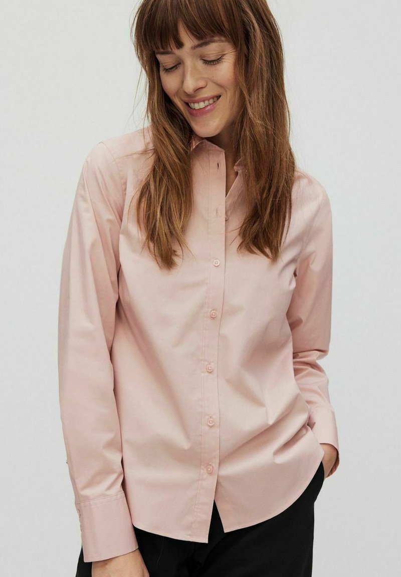 Chemise button-up rose clair à manches longues en tissu léger, dotée d'un col classique, de boutons sur le devant et de poignets ajustés.