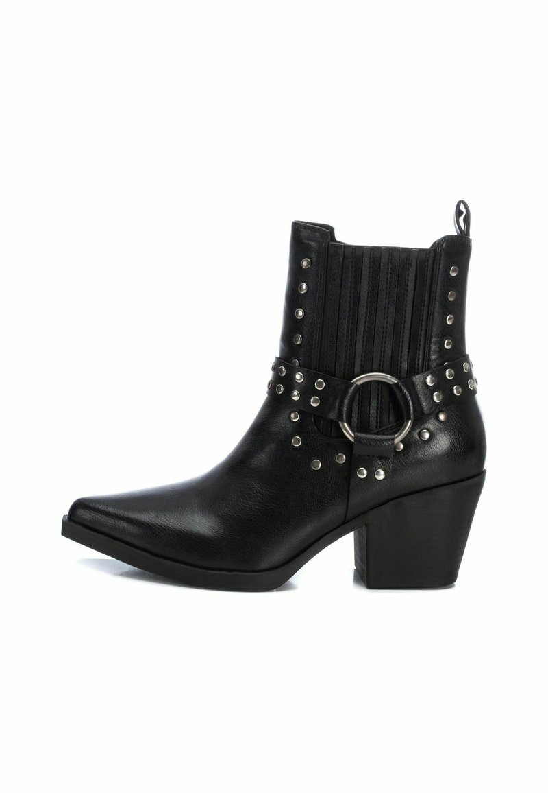 Stivale alla caviglia in stile cowboy nero con punta appuntita, tacco a blocco, borchie decorative e una fibbia accentuata. Presenta pannelli laterali elastici.