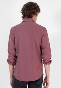 Camicia a maniche lunghe con bottoni in rosa polveroso. Tessuto in cotone con una sottile trama. Polsini arrotolati e dettaglio dell'orlo curvato sul retro.