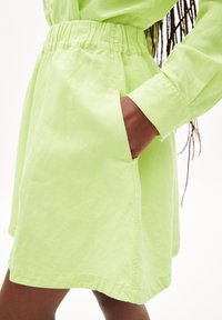 Jupe légère en coton mélangé, de couleur vert lime, avec une taille élastique, des poches latérales et une coupe décontractée. Ourlet simple et épuré.