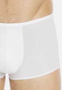 Boxer briefs bianchi realizzati in materiale trasparente, con un design aderente, vita elastica e cuciture a contrasto lungo i bordi.