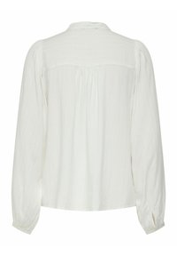 Blouse blanche à manches longues avec une texture à côtes verticales, col rond et détails froncés au dos. Poignets boutonnés avec des ouvertures fendue.