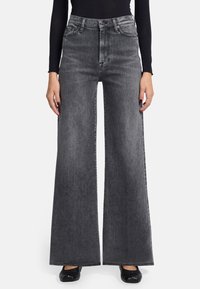 Jean en denim gris évasés à taille haute, avec un design classique à cinq poches et une texture légèrement déchirée.