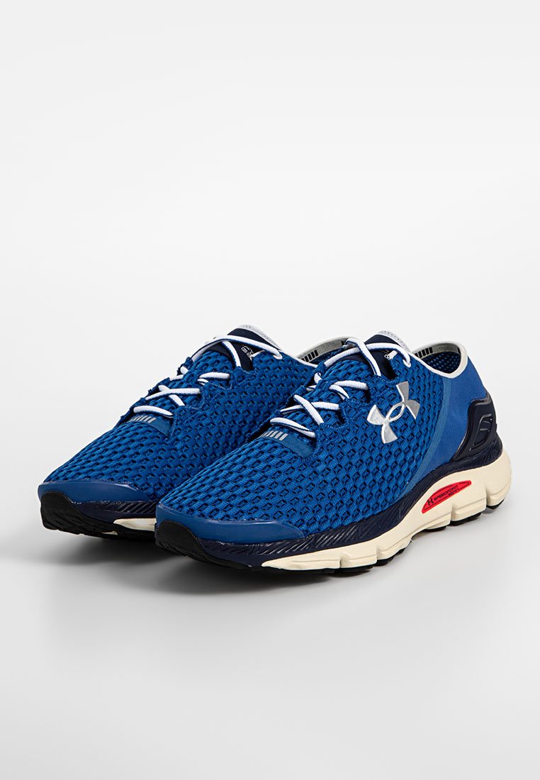 Zapatillas deportivas azules con parte superior de malla, cuello acolchado y cordones blancos. Cuentan con una suela acolchada con acentos rojos y un patrón texturizado.