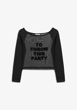 Zwarte cropped sweatshirt met gaas aan de voorkant, met opvallende, zwarte letters die "DIT FEEST WERKEN" lezen. Lange mouwen.