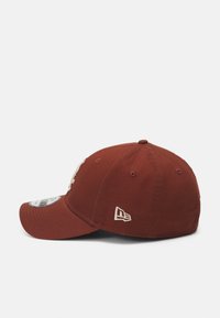 Casquette de baseball marron avec une visière courbée, logo brodé à l'avant et accents cousus. Tissu en coton et design classique à six panneaux.