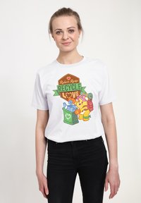 Biała bawełniana koszulka T-shirt z kolorową grafiką przedstawiającą niedźwiedzia z symbolami recyklingu, obok kosza na śmieci i napisu „Recycle Love”.