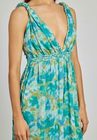 Maksy sukienka w niebiesko-zielonym wzorze tie-dye. Posiada plecione ramiączka i dekolt w serek, wykonana z lekkiego materiału.