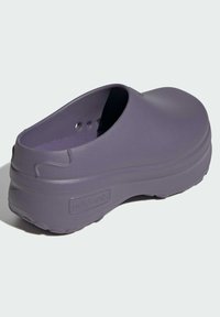 Zueco de goma morado con forma redondeada, suela gruesa y agujeros de drenaje en el lateral. Presenta un discreto logotipo en el lado.