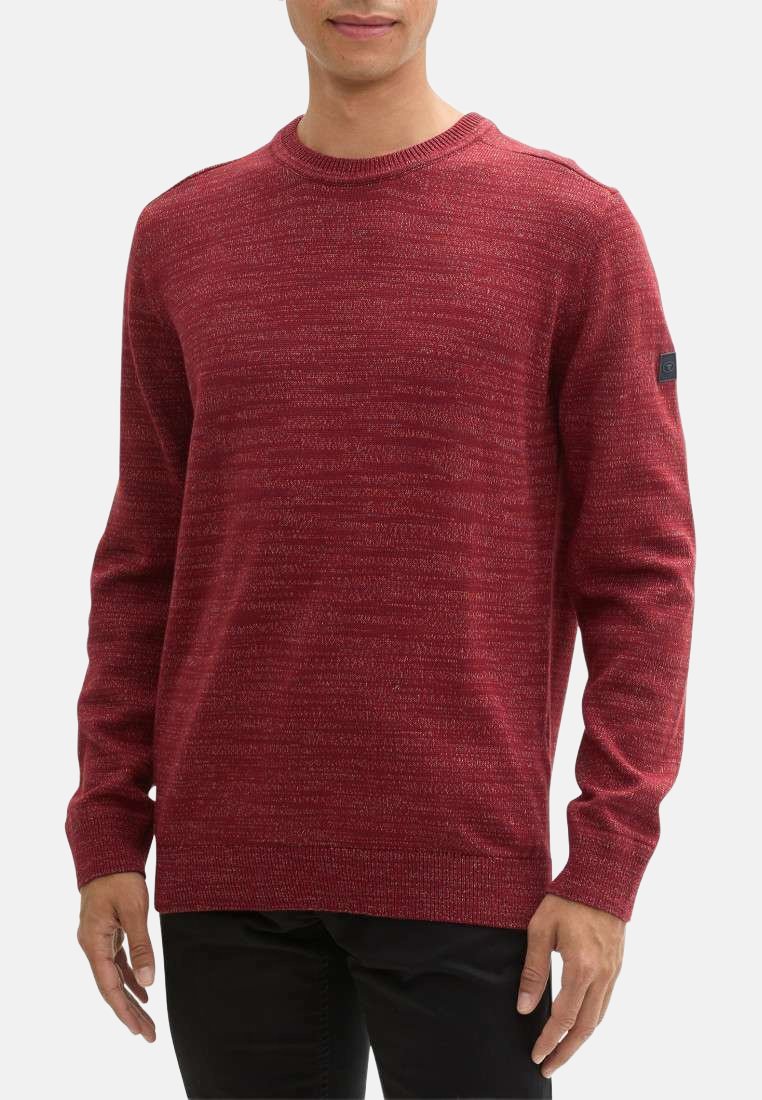 Pull en tricot rouge avec un col rond et des longues manches. Présente un motif texturé et un petit logo noir sur la manche gauche.