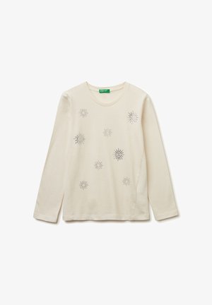 Camicia a maniche lunghe beige chiaro in cotone morbido con decorazioni argentee che assomigliano a stelle, dotata di un collo rotondo e spacchi laterali.