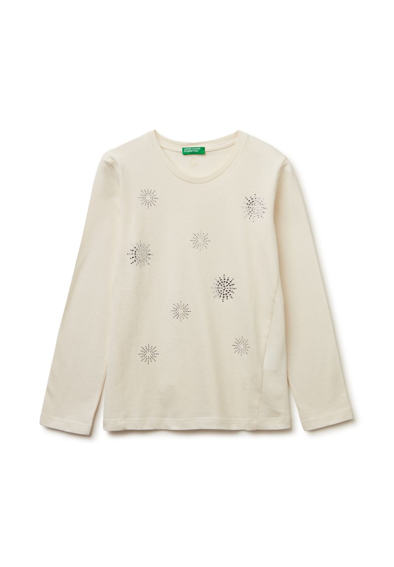 Helle beige Langarmbluse aus weichem Baumwollstoff mit dekorativen silbernen Verzierungen, die Sterne ähneln, mit rundem Halsausschnitt und Seitenschlitzen.