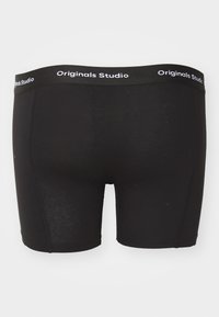 Sorte boksershorts med en glat tekstur, der har en bred sort taljehøjder mærket "Originals Studio" i hvid.