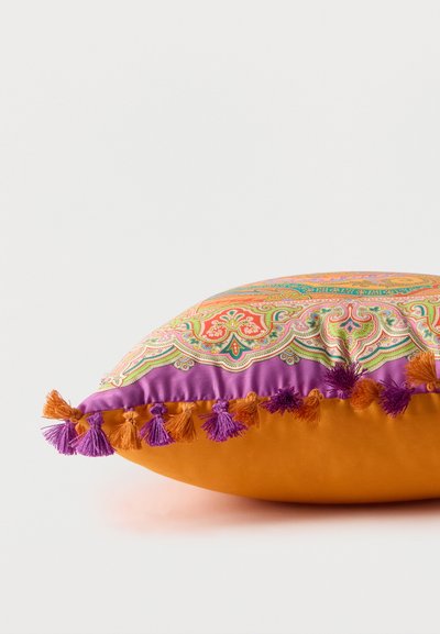 Coussin décoratif carré avec base orange, motif cachemire multicolore complexe, bordure violette et pompons orange et violets alternés sur les bords.