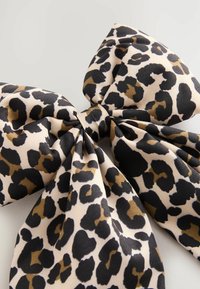 Fundă cu imprimeu de leopard realizată dintr-un material neted, având pete negre, maro și bej pe un fundal deschis de bej, cu un centru legat.