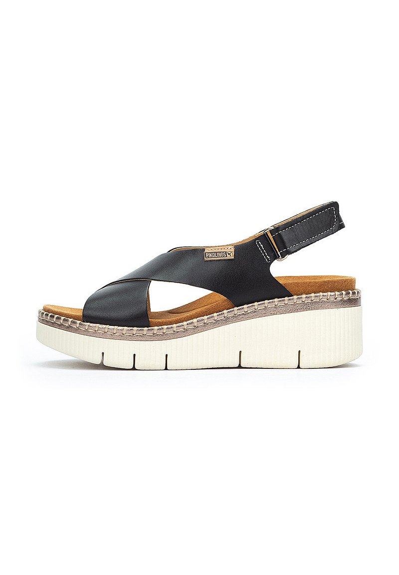 Sandalia de cuña de piel negra con diseño de tiras cruzadas, suela texturizada beige y correa para el talón ajustable. Forro interior suave.