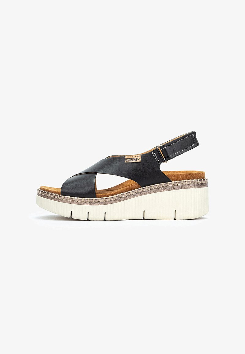 Sandalia de cuña de piel negra con diseño de tiras cruzadas, suela texturizada beige y correa para el talón ajustable. Forro interior suave.